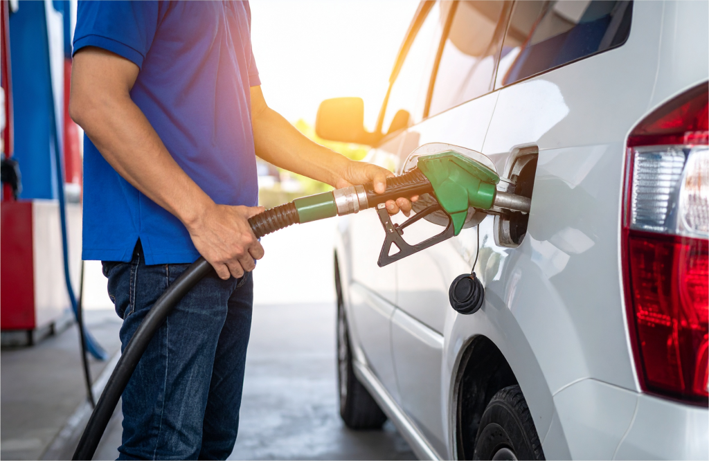 A driver and a car at a gas station. Image for a blog post explaining how to calculate fuel consumption.